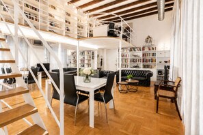 A modern interior with a staircase, a dining area, a sofa, and bookshelves. - 3 Bedroom, 3 bathrooms Quiet Flat + Cable Internet (Milano)