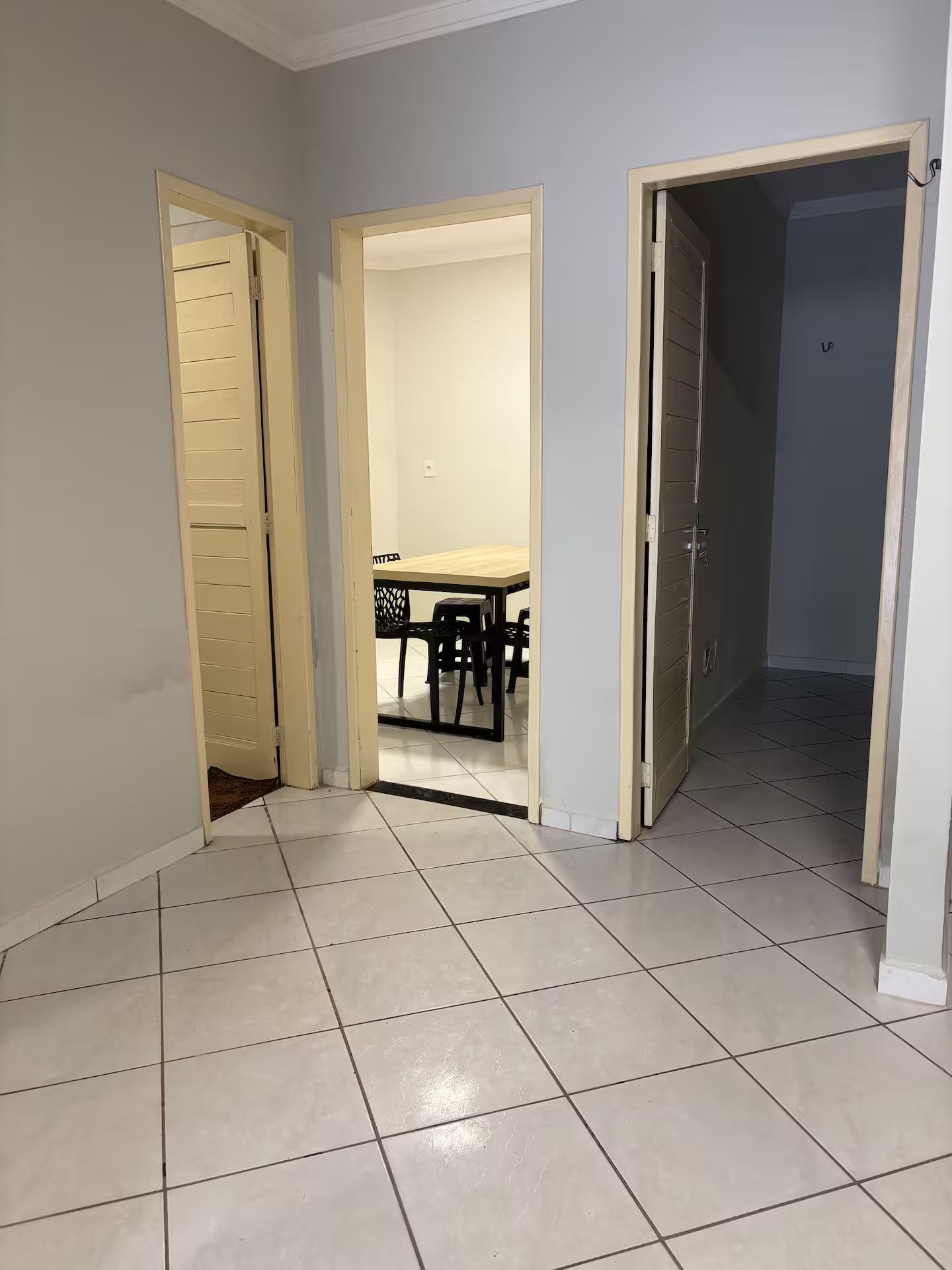 Un pasillo con suelo de baldosas que conduce a un comedor con mesa y sillas.