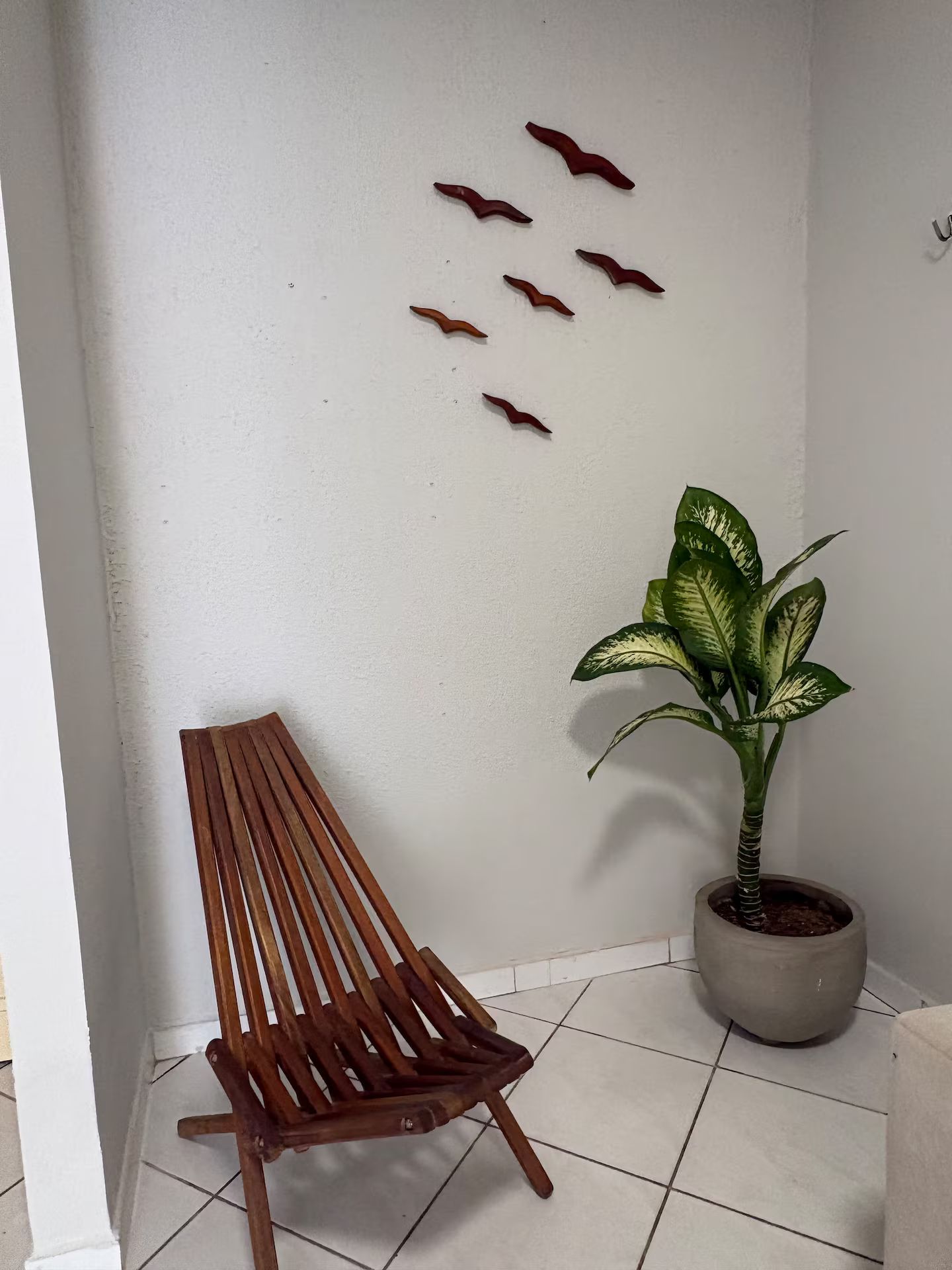 Canto com banco de madeira, planta em vaso e objetos decorativos na parede.
