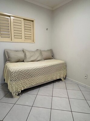 A bedroom with a bed, pillows, and a window with shutters.