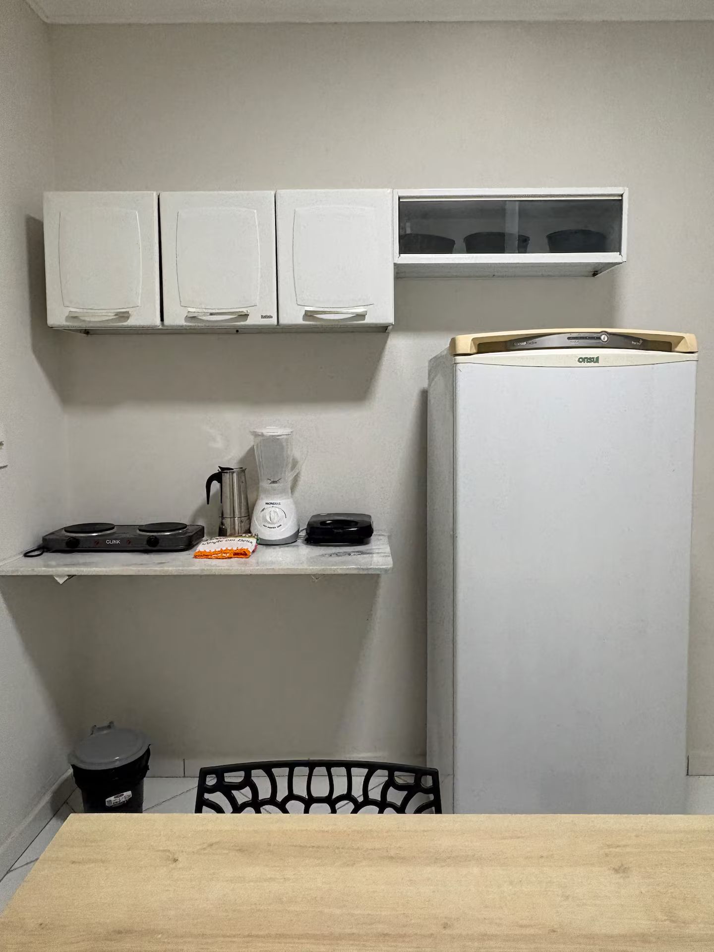 A compact kitchen with white cabinets, a built-in microwave, a coffee maker, and a refrigerator.