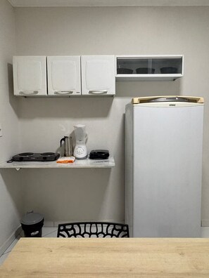 A compact kitchen with white cabinets, a built-in microwave, a coffee maker, and a refrigerator. - Alameda House - 2 bedrooms and private garage (Mossoró)