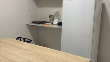 Eine kleine Küche mit Kühlschrank, Herd und Mikrowelle.