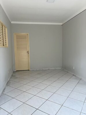 A room with a tiled floor, a door, and a light switch on the wall.