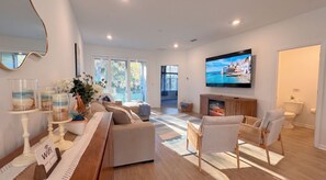 A modern living room with a fireplace, comfortable seating, and a large TV screen. - Pool | Jacuzzi | NO EXTRA FEE 5 min to beach (Palm Coast)