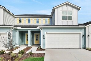 A two-story house with a garage, a front porch, and a small garden. - Pool | Jacuzzi | NO EXTRA FEE 5 min to beach (Palm Coast)