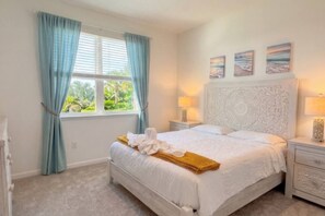A bedroom with a bed, two bedside tables, a window with curtains, and wall art. - Pool | Jacuzzi | NO EXTRA FEE 5 min to beach (Palm Coast)