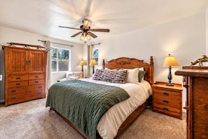 A bedroom with a bed, wooden nightstands, a ceiling fan, and a window. - Walk to the Lake | Hot Tub & Game Loft (South Lake Tahoe)