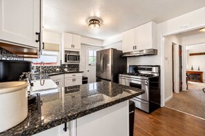 A modern kitchen with granite countertops, stainless steel appliances, and white cabinetry. - Walk to the Lake | Hot Tub & Game Loft (South Lake Tahoe)