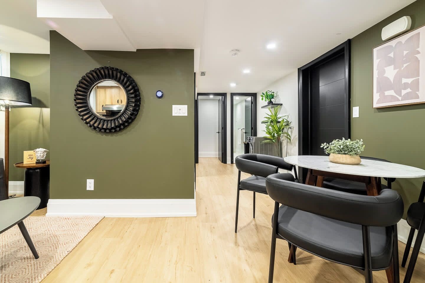 A modern dining area with a round table, black chairs, and a potted plant.