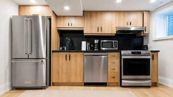 Una cocina moderna con electrodomésticos de acero inoxidable, armarios de madera y una encimera negra.