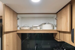 Una cocina con armarios de madera, encimera negra y utensilios de cocina blancos.