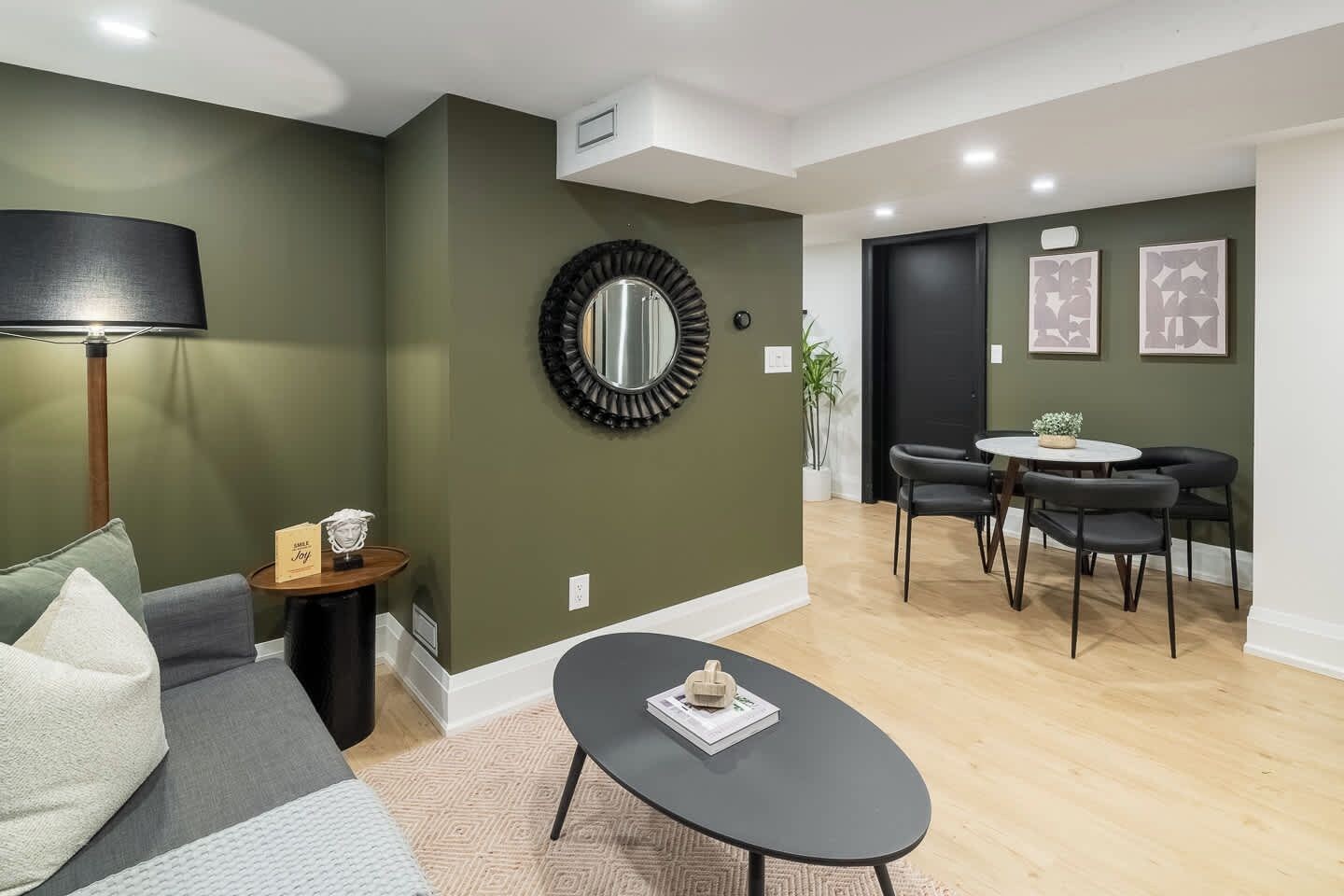 A modern living room with a sofa, coffee table, and a dining area with chairs and a table.