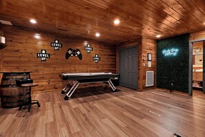 Een kamer met houten lambrisering, een pooltafel, een bar en een neonreclame.