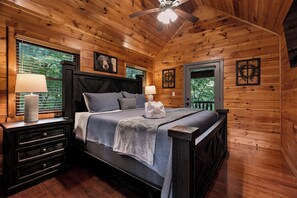 Een slaapkamer in een houten chalet met een bed, nachtkastjes en een plafondventilator.