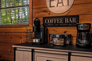 Een koffiebar met een bord, een koffiezetapparaat, een koffiemolen en koffiepads.