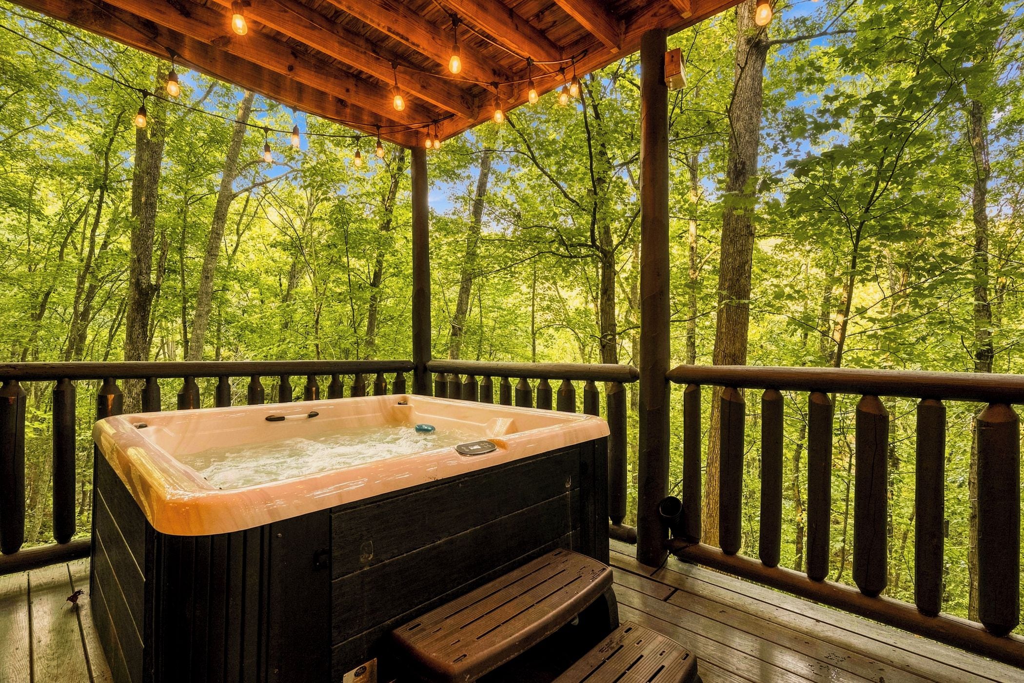 Ein Whirlpool auf einer Holzterrasse mit Blick auf einen Wald.