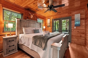 Ein Schlafzimmer einer Holzhütte mit einem Bett, Nachttischen und einem Deckenventilator.