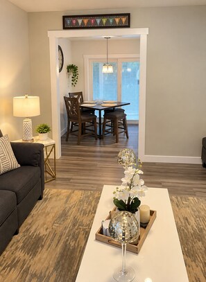 A living room with a sofa, coffee table, lamp, and a dining area with chairs and a table. - Spacious 4-bedroom house in gorgeous Kennewick with AC (Kennewick)