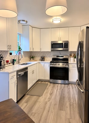 A modern kitchen with white cabinets, stainless steel appliances, a built-in oven, and a dishwasher. - Spacious 4-bedroom house in gorgeous Kennewick with AC (Kennewick)