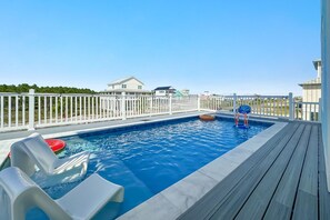 A swimming pool with a wooden deck, a white fence, and a house in the background. - New Beginnings · New Lux Home*Private Pool*100ft to Beach*Elevator (Gulf Shores)