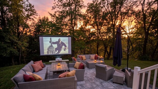 An outdoor seating area with a flat-screen TV, wicker furniture, and a stone patio. - Riverfront Front | Fire Pit | Arcade | Fishing| (New Brunswick)
