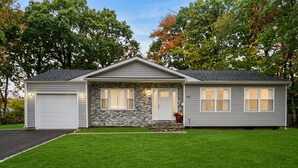 A single-story house with a stone facade, a front porch, and a garage. - Riverfront Front | Fire Pit | Arcade | Fishing| (New Brunswick)