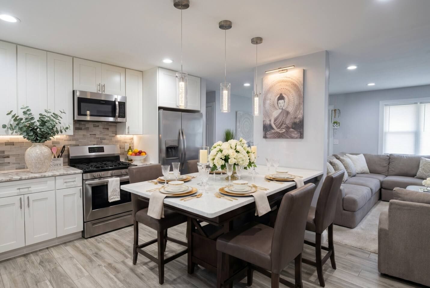 Una cocina moderna con armarios blancos, electrodomésticos de acero inoxidable y una zona de comedor con una mesa vestida para cuatro.