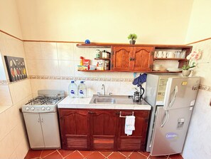 Eine kleine Küche mit Gasherd, Spüle und Kühlschrank.