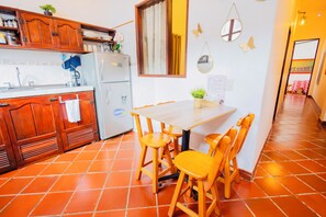 A kitchen with wooden cabinets, a refrigerator, and a dining table with chairs.