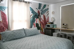 Ein Schlafzimmer mit einem Bett, einem Schreibtisch, einer Mikrowelle und einem Mülleimer.