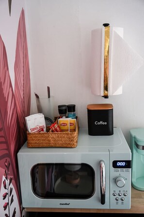 Eine Mikrowelle mit einer Snackauswahl und einer Kaffeemaschine darauf.