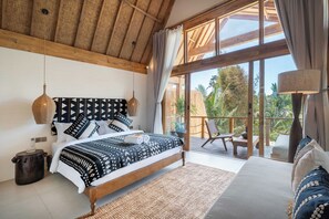 Ein Schlafzimmer mit einem großen Bett, einer Holzbalkendecke und Blick ins Freie.