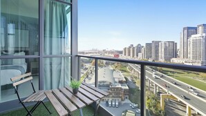 Un balcón con vista a un paisaje urbano, una mesa de madera y una silla.