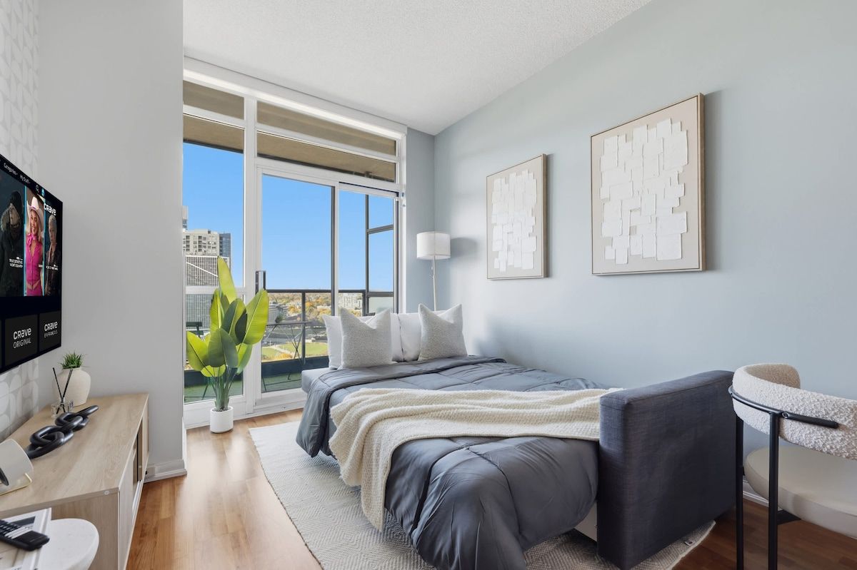 A modern bedroom with a bed, a desk, a chair, and a television.