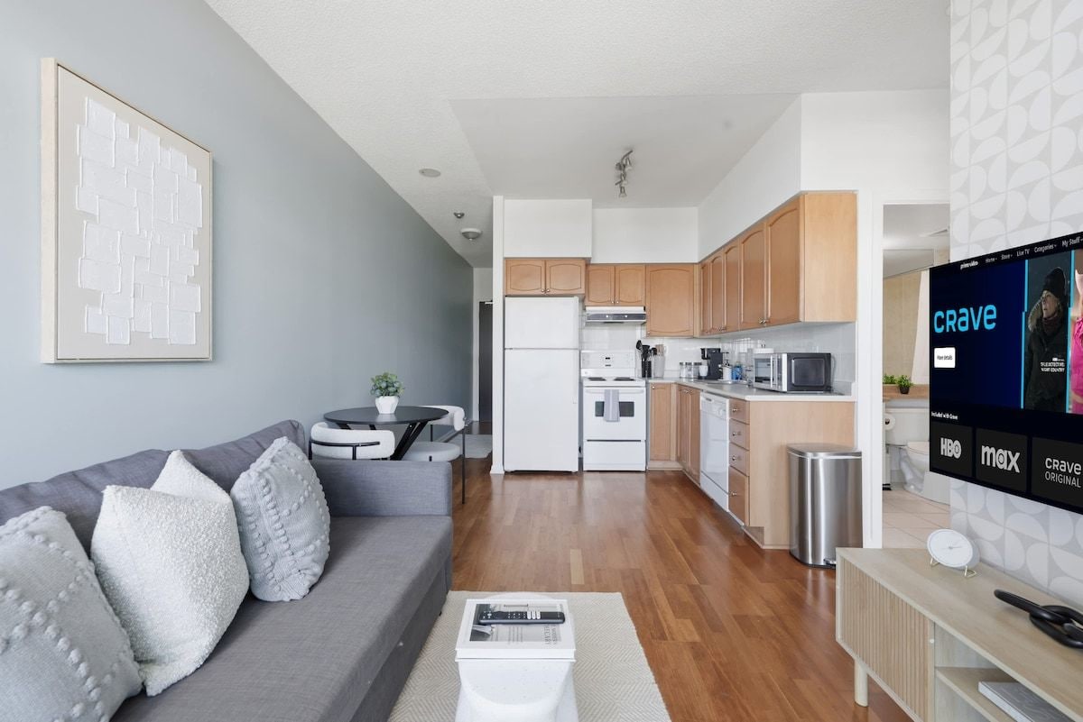 A modern living room with a grey sofa, a coffee table, and a TV displaying the HBO network.