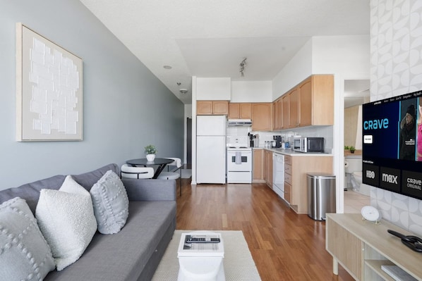A modern living room with a grey sofa, a coffee table, and a TV displaying the HBO network.