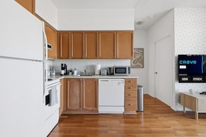 A modern kitchen with wooden cabinets, a white refrigerator, a microwave, and a dishwasher.