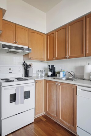 A kitchen with wooden cabinets, a white stove, a coffee maker, and a sink.