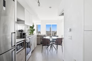 Une cuisine moderne avec un coin repas, de grandes fenêtres et une vue sur la ville.