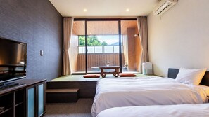 Quarto de hotel com cama, televisão, janela com cortinas e vista para o exterior.
