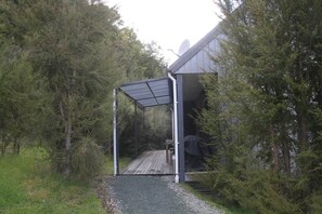 A covered outdoor area with a wooden deck leading to a building with a satellite dish.