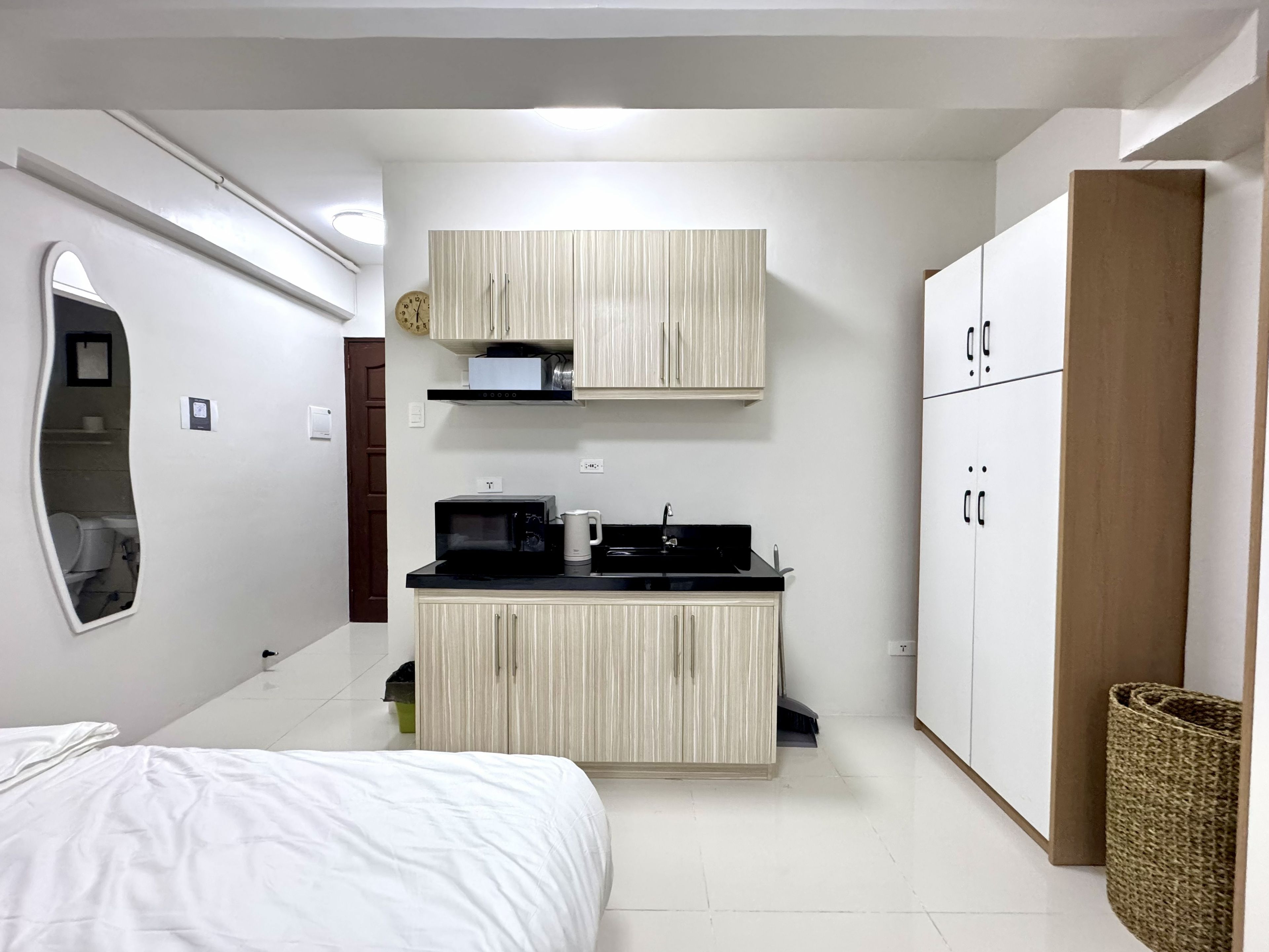 A compact bedroom with a bed, a small kitchenette, and a wardrobe.