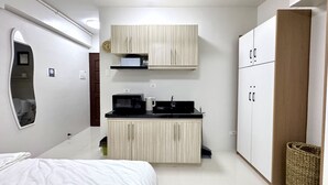 A compact bedroom with a bed, a small kitchenette, and a wardrobe. - Royal Oceancrest Panglao 1 (Dauis)