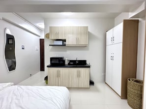 A compact bedroom with a bed, a small kitchenette, and a wardrobe. - Royal Oceancrest Panglao 1 (Dauis)