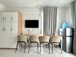 A modern kitchen with a flat-screen TV, a refrigerator, and a dining area with chairs. - Royal Oceancrest Panglao 1 (Dauis)