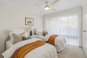 A hotel room with two beds, a ceiling fan, a window with sheer curtains, and a framed picture on the wall. - Lakeview@macs by Coast Hosting (MacMasters Beach)