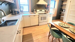 Una cucina moderna con mobili bianchi, forno a incasso e zona pranzo con tavolo in legno e sedie verdi.