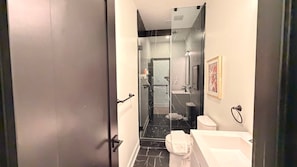 A modern bathroom with a glass-enclosed shower, a white sink, and a toilet.