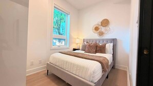 Une chambre à coucher avec un lit, une fenêtre et un luminaire fixé au mur.